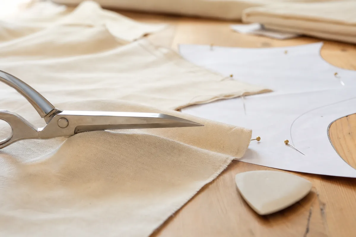 Sewing scissors cutting a piece of fabric placed on a paper pattern